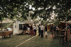 a group of people standing next to each other in front of a food truck on a field