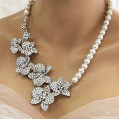 Elevate your bridal look with our Bridal Statement Earrings Necklace Set. Crafted with stunning crystal pearls and intricate orchid flowers, this unique wedding jewelry set adds a touch of elegance to your special day. Designed as the perfect gift for brides, each piece reflects meticulous attention to detail and timeless beauty. Let our set be a cherished part of your unforgettable moments. Embrace authenticity and sparkle with this exquisite ensemble. Dazzle on your special day with our exquis White Crystal Embellished Bridal Earrings For Wedding, White Flower Bridal Necklace For Wedding, White Floral Bridal Necklace For Wedding, Silver Flower Bridal Necklace For Wedding, Flower Crystal Wedding Necklace, White Crystal Embellished Bridal Necklace, Wedding Crystal Flower Necklace, White Crystal Embellished Bridal Necklace For Wedding, Wedding Crystal Necklace With Flower Design