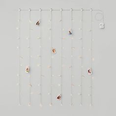 a white wall hanging with pictures on it and string lights attached to the side of it