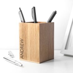 a wooden pen holder with three pens in it