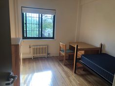 an empty room with a bed, desk and window