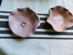 two pink ceramic bowls sitting on top of a striped table cloth next to each other