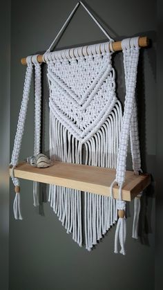 a macrame wall hanging on a wooden shelf