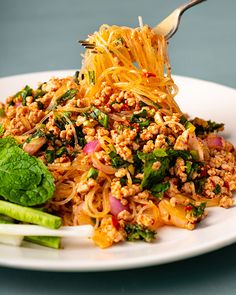 a white plate topped with noodles and veggies on top of a blue table