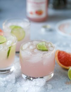 three glasses filled with pink lemonade and garnished with limes on ice