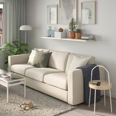 a living room filled with furniture next to a window and a plant on the wall