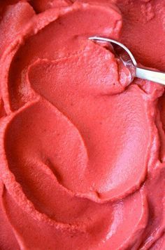 a close up of a spoon in a bowl of red cake frosted with icing