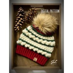 a crocheted hat with a pom - pom sits in a box