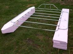 a white bench sitting on top of a green grass covered field next to a metal frame