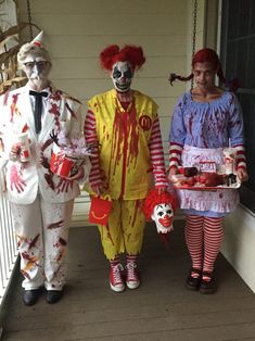 three people dressed up as zombies and clowns on the front porch with food in their hands