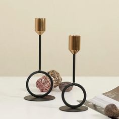 two black and gold candlesticks sitting next to each other on a white table