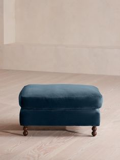 a blue footstool sitting on top of a hard wood floor next to a wall