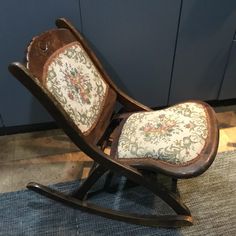 a wooden rocking chair with floral fabric on it's back and seat padding