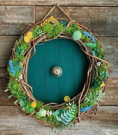 a wreath made out of branches and plants on a wooden wall with a green door