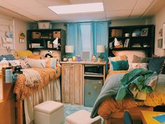 two beds in a dorm room with blue and yellow decor on the walls, one bed is made up