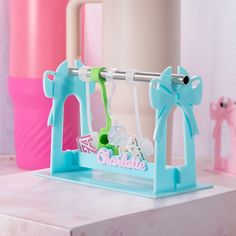 a blue plastic toy set on top of a white table next to pink and green vases