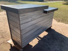 a large wooden box sitting in the middle of a dirt field next to a grass covered field