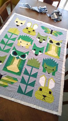 a quilted table runner with animals and leaves on it, sitting on top of a dining room table