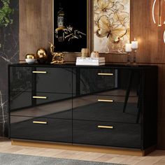 a black and gold sideboard in a living room with art on the wall behind it