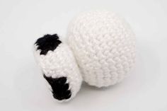 a crocheted black and white object on a white surface with one ball in the foreground