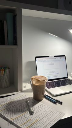 an open laptop computer sitting on top of a desk next to a cup of coffee