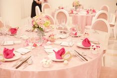 the table is set with pink napkins and flowers