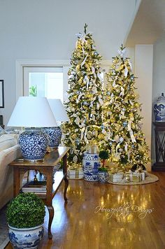 two decorated christmas trees sitting on top of a hard wood floor in a living room