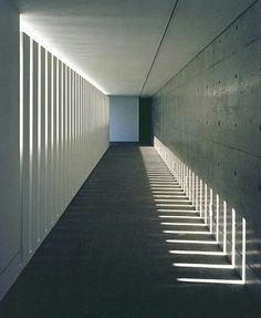 an empty hallway with long shadows on the wall