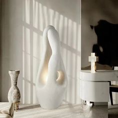 a large white vase sitting on top of a table next to a small vase with a light in it