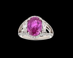 an oval shaped pink sapphire and diamond ring with two shoulders, set in 18k white gold