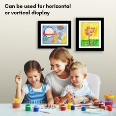 a woman and two children sitting at a table with art supplies in front of them