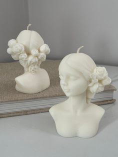 two white ceramic head vases sitting next to each other on top of a book