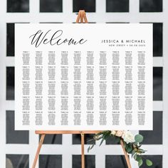 a welcome sign with flowers and greenery sits on top of a wooden easel