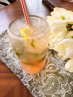 there is a drink on the table next to some flowers