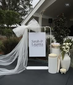 a white sign sitting on top of a table next to vases