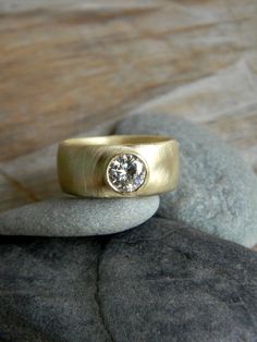 a gold ring sitting on top of a rock with a diamond in it's center