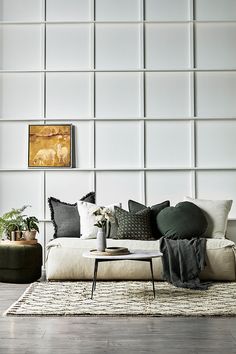 a living room filled with lots of furniture next to a wall covered in white tiles