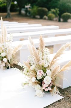 two white benches sitting next to each other covered in flowers and pamonini plants