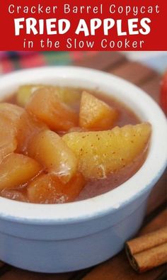 a white bowl filled with sliced apples on top of a wooden table next to cinnamon sticks