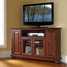 a flat screen tv sitting on top of a wooden entertainment center next to a window