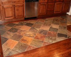 a kitchen with wooden cabinets and tile flooring on the counter top, along with a stainless steel dishwasher