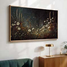 a painting hanging on the wall next to a green couch and table with a lamp