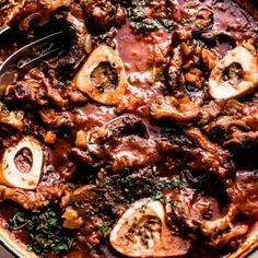 a skillet filled with meat and mushrooms covered in sauce, garnished with parsley