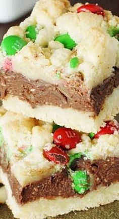 three pieces of christmas cookie bars stacked on top of each other with candy and marshmallows