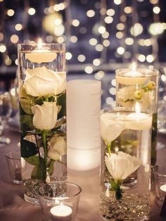 two vases filled with white roses and candles