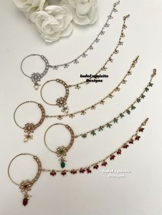 four different types of hoop earrings and necklaces with flowers on the table in the background