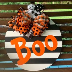 a decorated boo sign sitting on top of a wooden bench