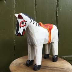 a wooden horse statue sitting on top of a wooden table next to a green wall