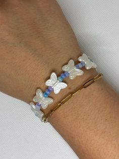 a woman's arm wearing a bracelet with butterfly charms and beads on the wrist