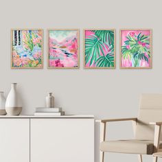 three paintings hang on the wall next to a white cabinet and chair in a room